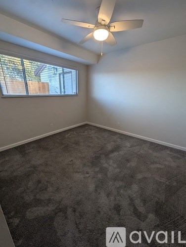 A room with a carpeted floor and a ceiling fan.