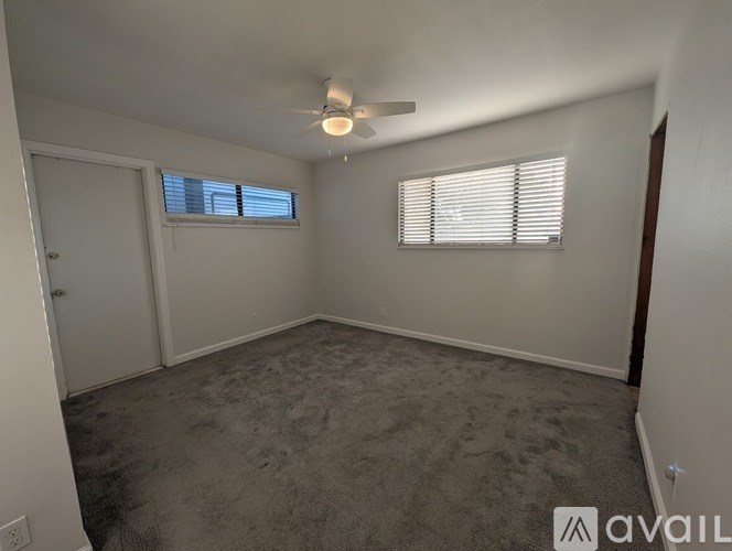A spacious room with a ceiling fan and a window with blinds.