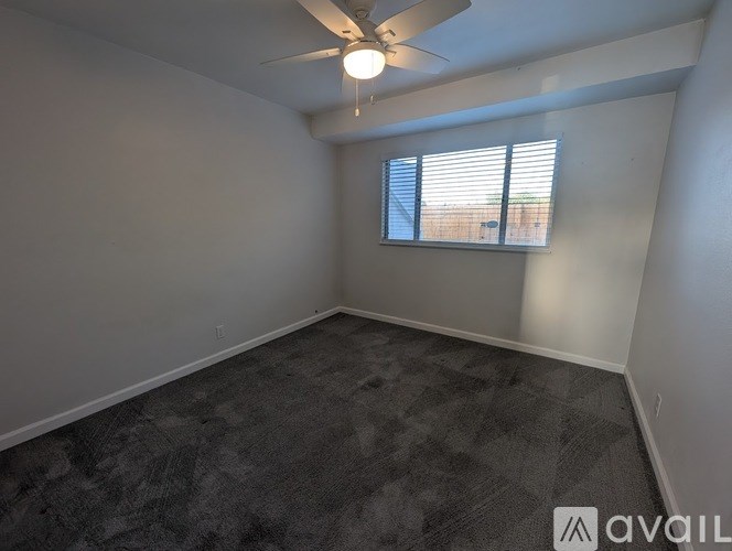 A room with a ceiling fan and a window with blinds.