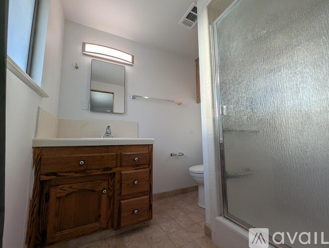 A bathroom with a wooden vanity and a glass shower door.