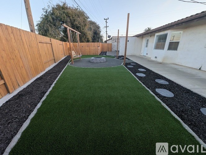 A backyard with a green lawn and a wooden fence.