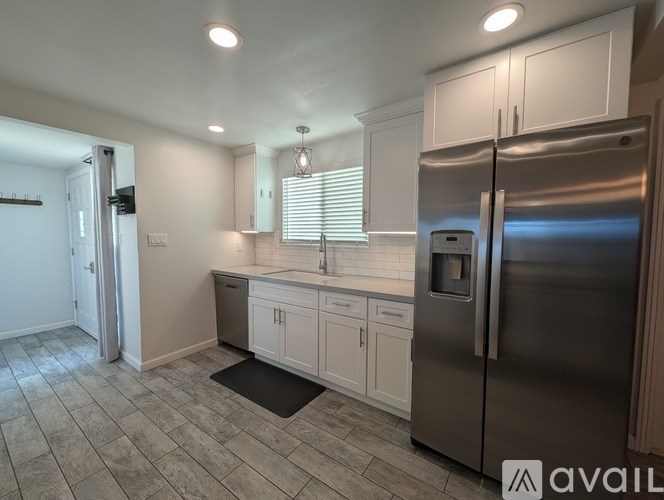 A kitchen with a refrigerator, sink, and cabinets.