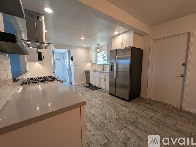 A modern kitchen with a stainless steel refrigerator and a wooden floor.