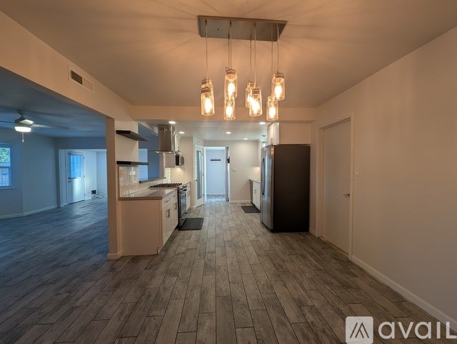 A spacious kitchen and living room with wooden flooring and modern lighting fixtures.
