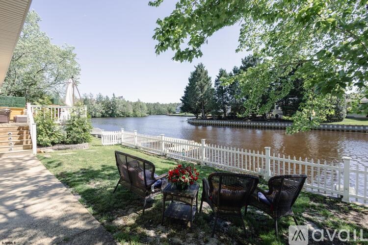 A patio with chairs and a table overlooking a lake.