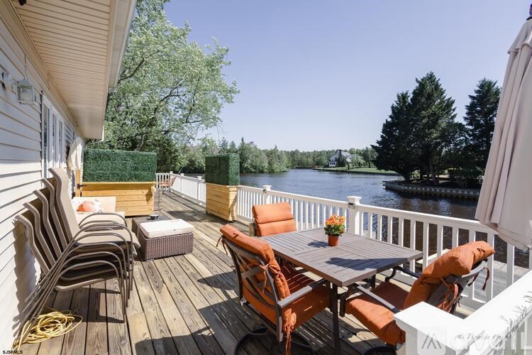 A wooden deck with chairs and a table overlooking a body of water.