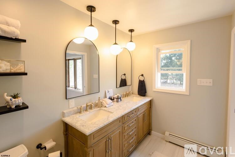 A bathroom with a large mirror, two sinks, and a window.