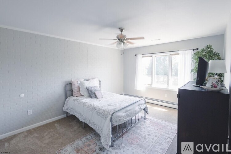 A bedroom with a bed, dresser, and window.