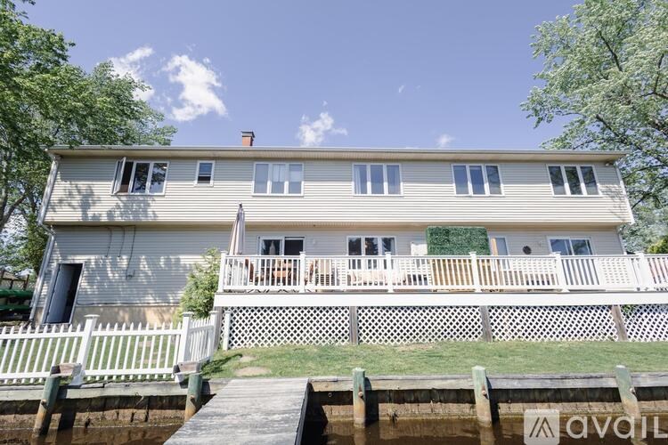 A two-story house with a deck and a dock in front.