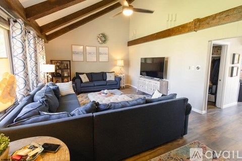 A living room with a dark blue couch and a wooden ceiling.