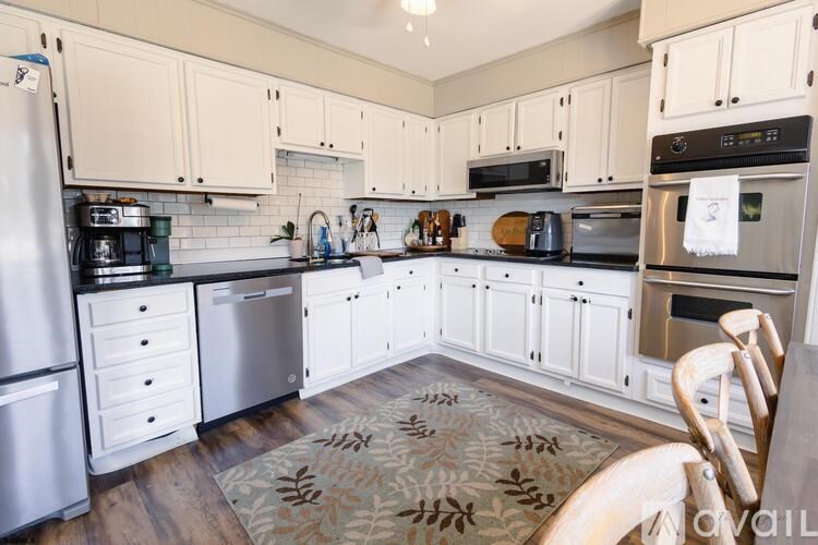 A kitchen with white cabinets and a rug on the floor.