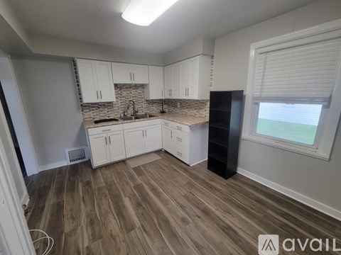 A kitchen with white cabinets and a stone backsplash is available.