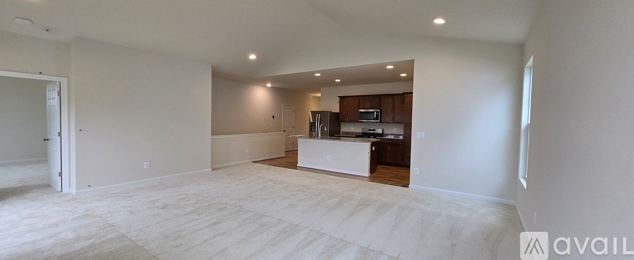 A spacious living room with a kitchen in the background.