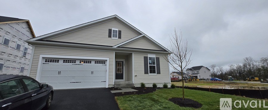 A house with a garage and a tree in front of it.