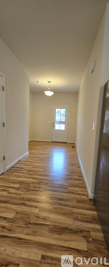A long hallway with wooden floors and a light on.