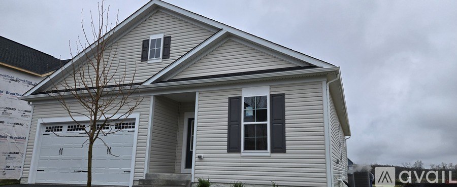 A house with a garage door and a tree in front of it.