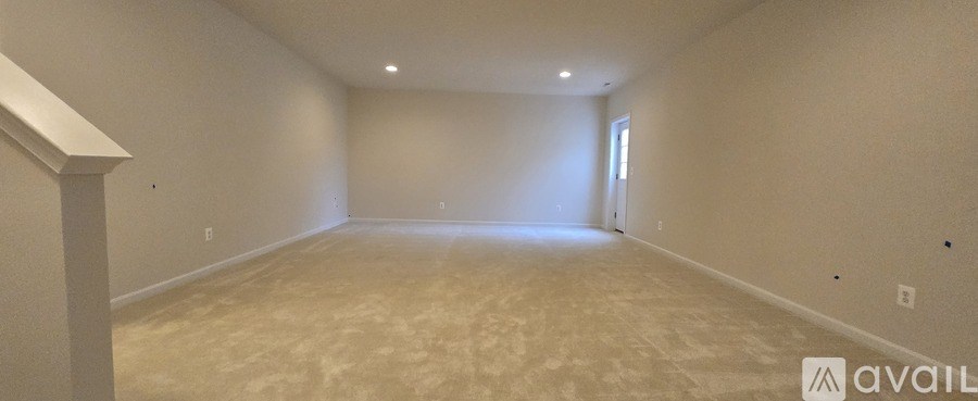 A spacious empty room with a carpeted floor and white walls.