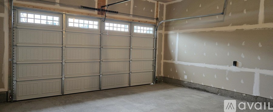 A large garage door is closed and the wall is unfinished.