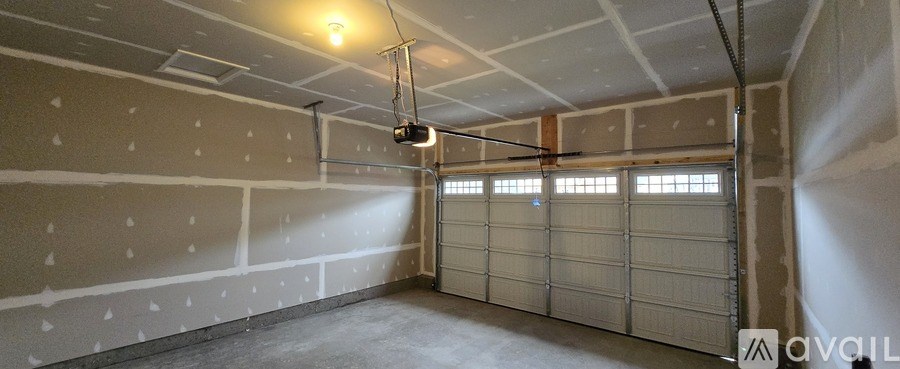 A sparsely furnished garage with a hanging light fixture and a window.