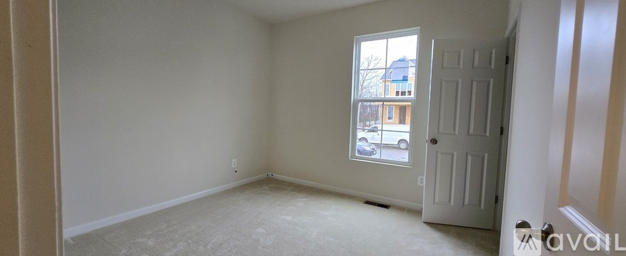 A room with a carpeted floor and a window showing a building outside.