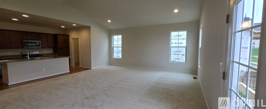 A spacious living room with a kitchen area and a large window.