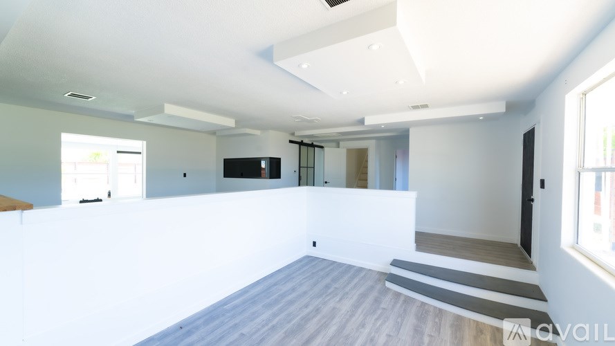 A spacious, empty room with a white ceiling and a striped rug on the floor.