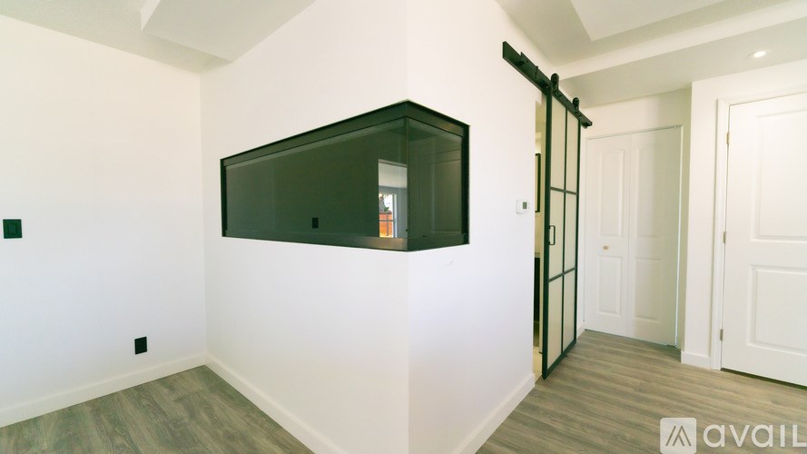 A room with a white wall and a black framed mirror on the wall.