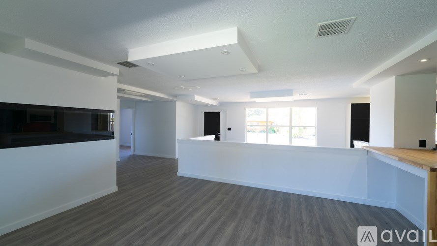 A spacious room with a wooden floor and white walls.
