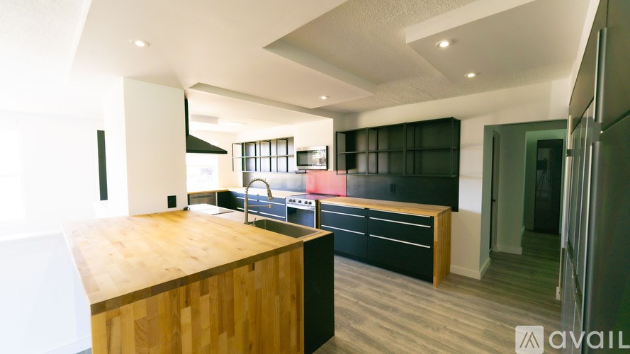 A kitchen with a wooden counter top and black cabinets.