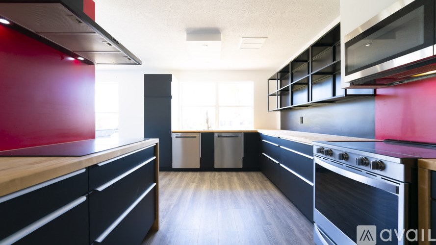 A modern kitchen with black cabinets and a red accent wall.