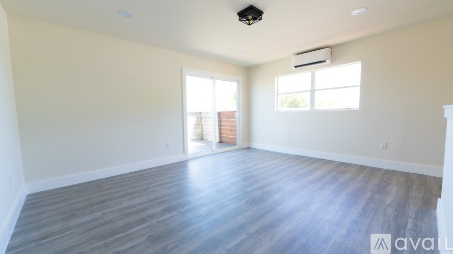 A spacious room with wooden flooring and a ceiling fan.