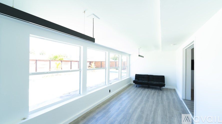 A spacious living room with a black sofa and large windows.