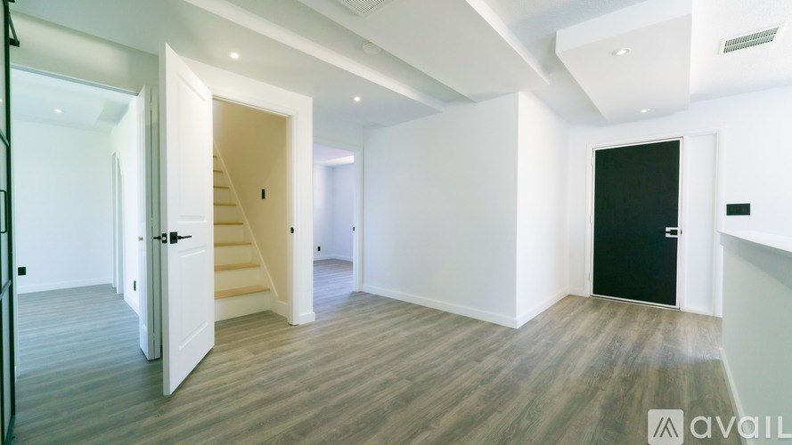 A spacious room with wooden flooring and a staircase leading to another level.