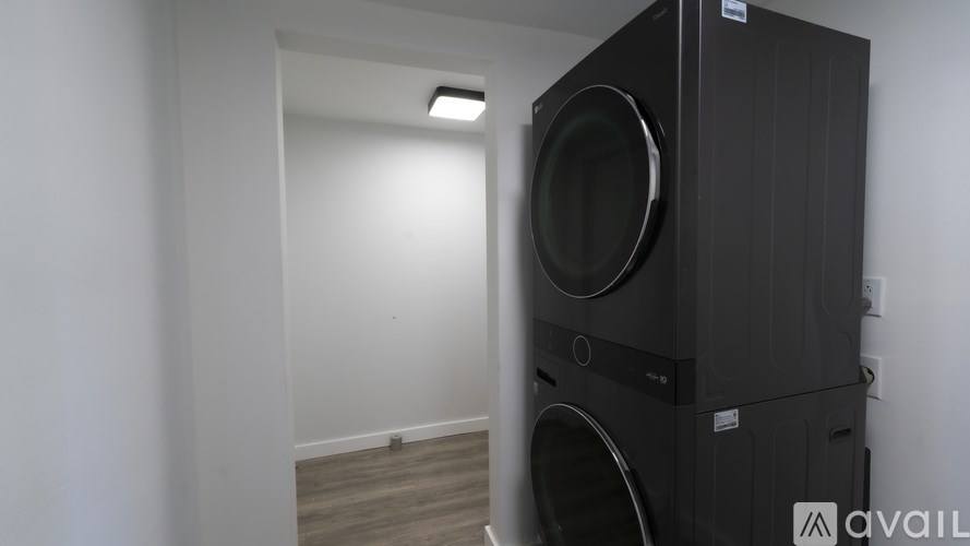 A black speaker stands in a room with a wooden floor.