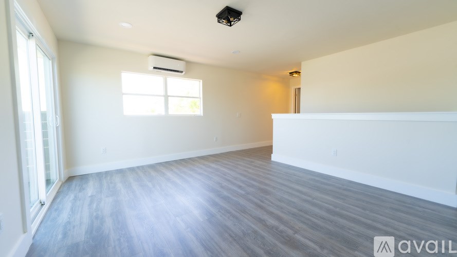 A spacious room with a window and a ceiling fan.