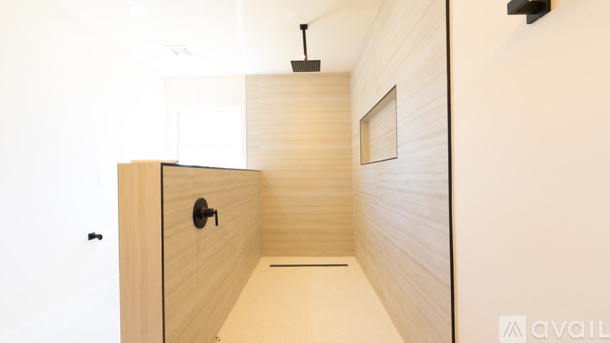 A wooden door with a black handle is in a room with wooden walls.