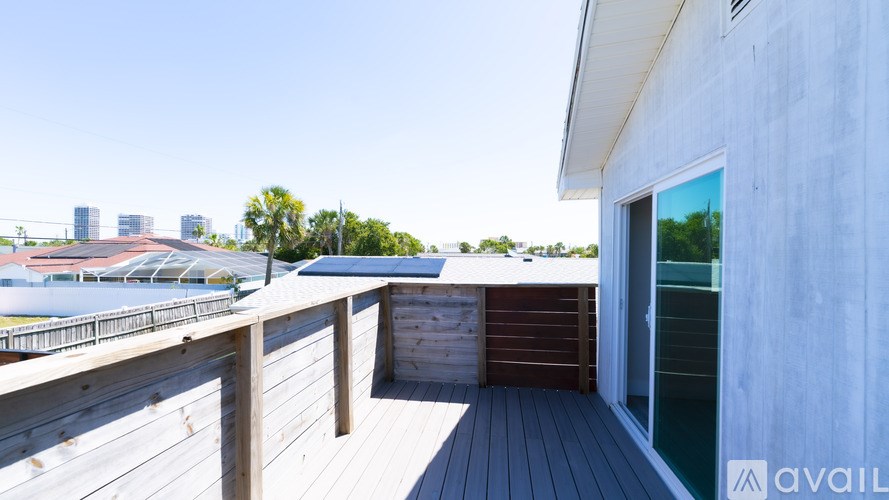 A wooden deck with a railing and a building in the background.