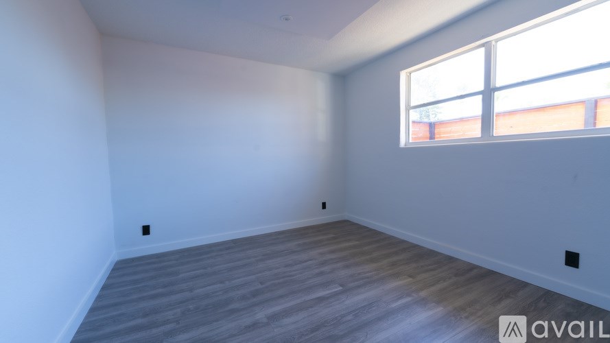 A room with a window and wooden flooring is available for rent.