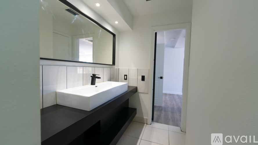 A bathroom with a sink, mirror, and a door.