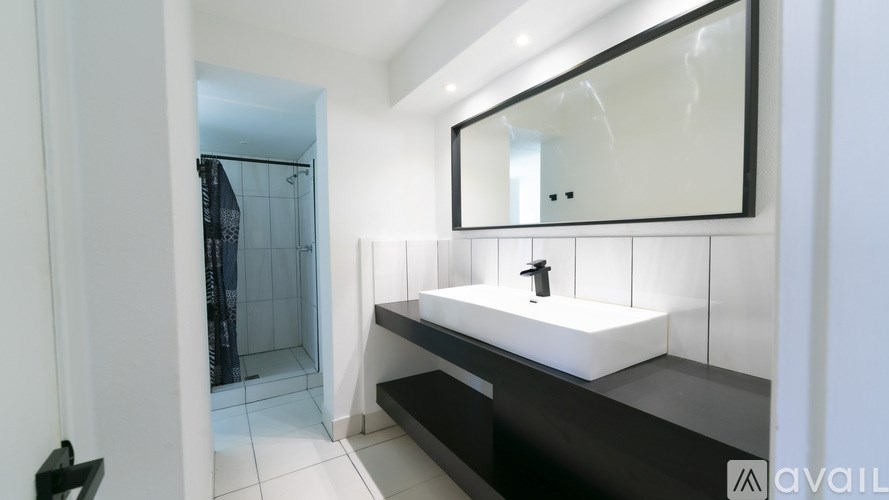 A bathroom with a sink, mirror, and shower.