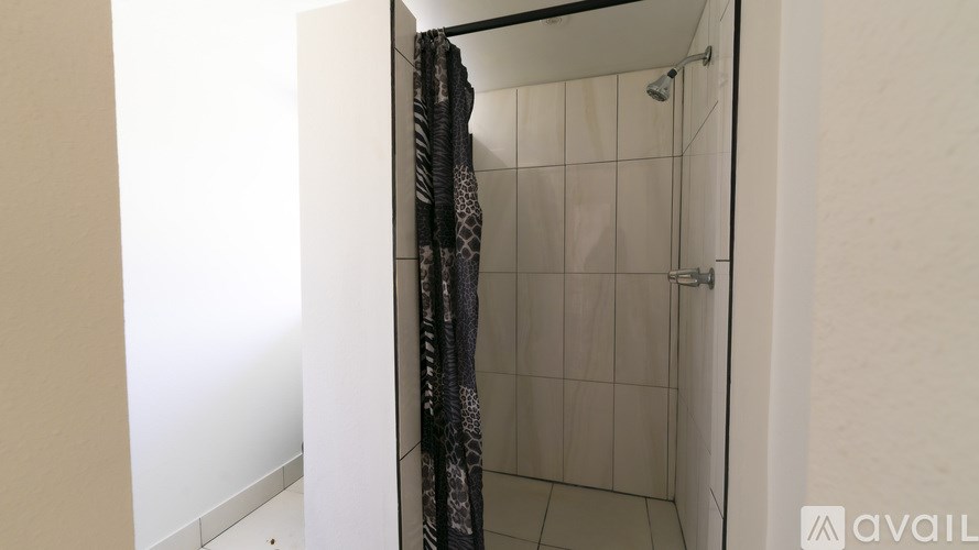 A bathroom with a shower and a towel hanging on the door.