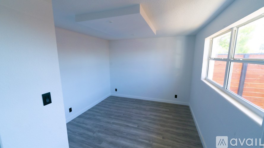 A room with a window and wooden flooring is available for rent.