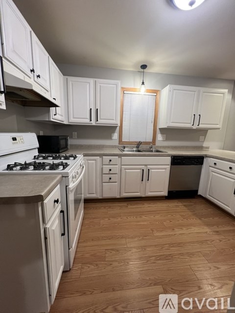 A kitchen with white cabinets and a wooden floor.