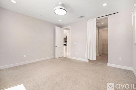 A spacious room with a carpeted floor and a sliding door leading to another room.