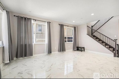 A spacious room with a marble floor and a staircase.