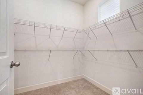 A white closet with a carpeted floor and a white door.