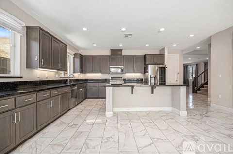 A spacious kitchen with dark brown cabinets and a marble floor.