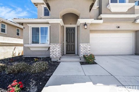 A beige house with a black front door and a white garage door.