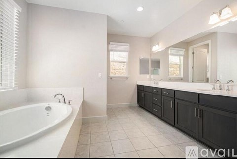 A bathroom with a white tub and black cabinets.