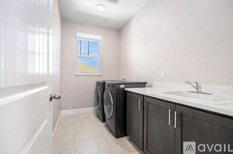 A laundry room with a washer and dryer, a window, and a sink.